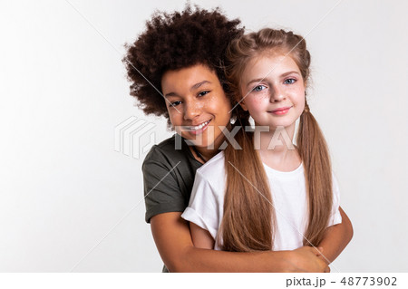 Cheerful dark-haired little boy tightly hugging his friend Cheerful dark-haired little boy tightly hugging his friend 48773902