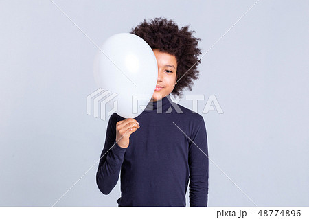 Pretty young man with afro hairstyle closing half of his face with balloon Pretty young man with afro hairstyle closing half of his face with balloon 48774896