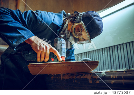 Carpenter using circular saw for cutting wooden boards. 48775087