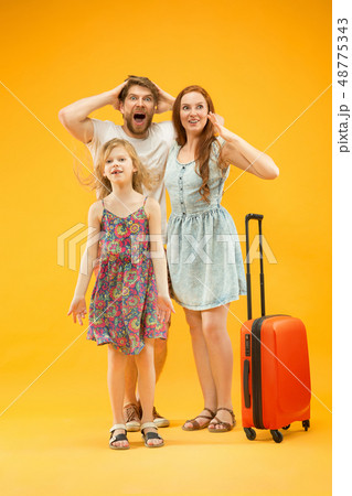 Happy parent with daughter and suitcase at studio isolated on yellow background 48775343