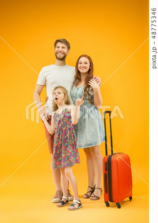 Happy parent with daughter and suitcase at studio isolated on yellow background 48775346