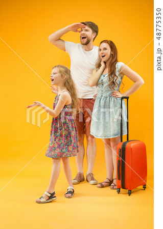 Happy parent with daughter and suitcase at studio isolated on yellow background Happy parent with daughter and suitcase at studio isolated on yellow background 48775350