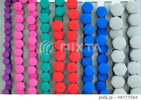 A lot of colorful dumbbell on stand 48777564