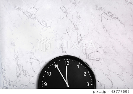 Black wall clock on white marble background 48777695