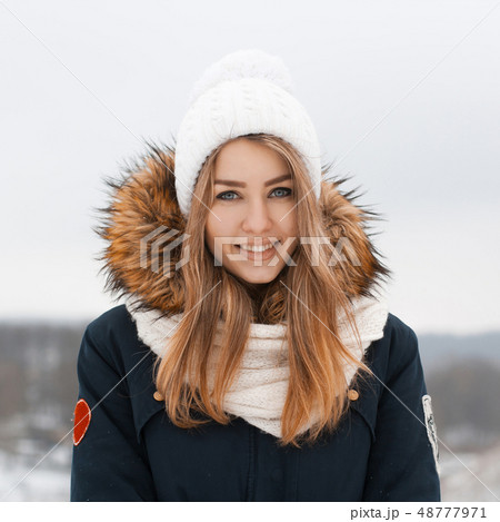 Sweet girl in a knitted hat and jacket smiles. 48777971