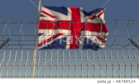 Defocused waving flag of Great Britain behind barbed wire fence. 3D rendering 48780524