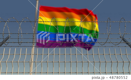 Barbed wire against blurred waving gay pride flag. LGBT oppression conceptual 3D rendering Barbed wire against blurred waving gay pride flag. LGBT oppression conceptual 3D rendering 48780552