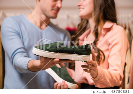 Female and male hand holds green moccasins. 48780881