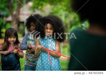 Happy children playing tug of war in the park. Happy children playing tug of war in the park. 48785004