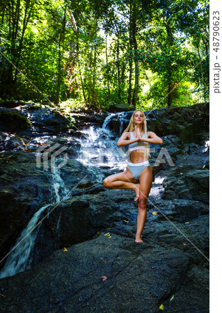 Young woman practicing yoga with waterfall on the Young woman practicing yoga with waterfall on the 48790623