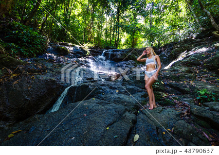 Young woman is posing at small waterfall Young woman is posing at small waterfall 48790637