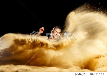 Female long jump athlete landing in sandpit Female long jump athlete landing in sandpit 48795444