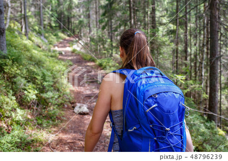 Young smiling woman with backpack hiking in forest 48796239
