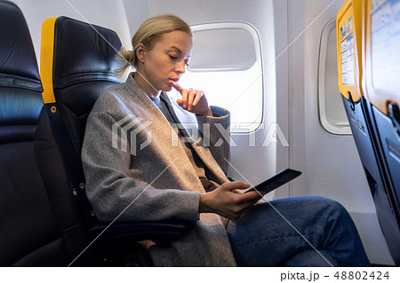 Woman reading on digital e-reader while traveling by airplane. 48802424