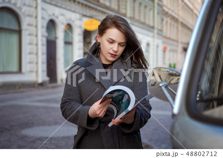 Happy fashion woman reading a magazine on a city Happy fashion woman reading a magazine on a city 48802712