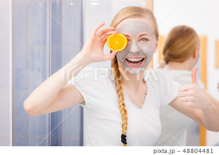 Happy young woman having face mask holding kiwi 48804481