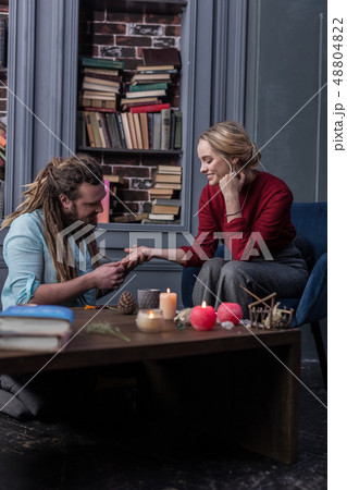 Joyful good looking woman sitting in front of the chiromancer 48804822