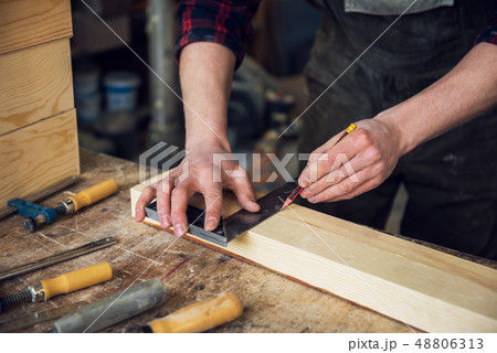 The worker makes measurements of a wooden board 48806313