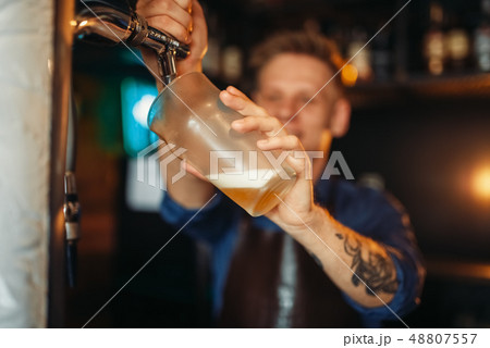 Male barman pouring beer at the bar counter 48807557