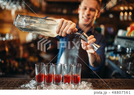 Male barman in apron prepares alcoholic coctail 48807561