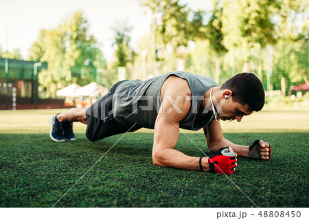 Man doing push-up exercise on a grass outdoor 48808450