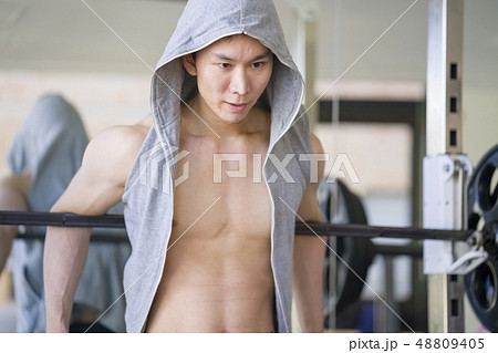 ベンチプレス後にマシンに寄りかかり休憩するストイックな男性トレーナーインストラクター 48809405