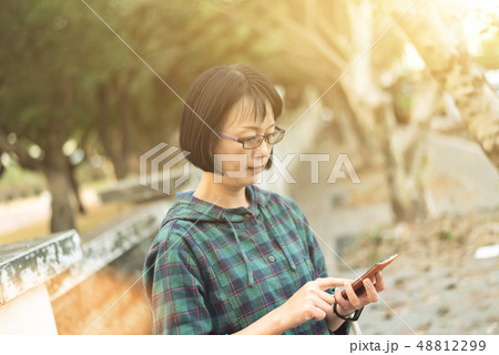 Asian mature woman using cellphone Asian mature woman using cellphone 48812299