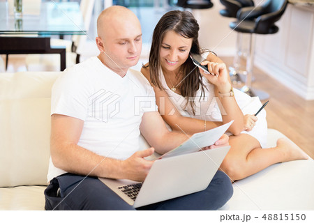 Young couple on the sofa with laptop and count the bill for payment. The concept of utilities, debt Young couple on the sofa with laptop and count the bill for payment. The concept of utilities, debt 48815150
