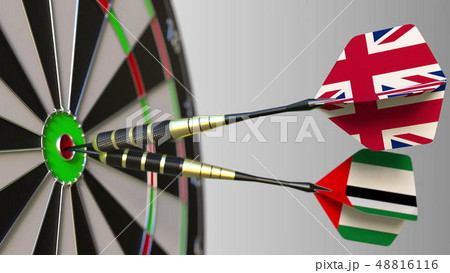 Flags of the United Kingdom and the UAE on darts hitting bullseye of the target. International 48816116