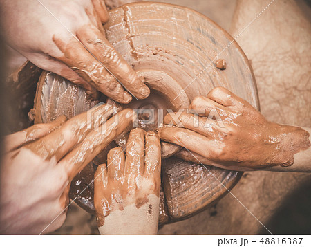 Teaching pottery A carftman's hands guiding a child hand, showing how to throw a clay pot on a 48816387