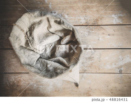 Burlap bag of white wholemeal flour on wooden rustic boards background top view Burlap bag of white wholemeal flour on wooden rustic boards background top view 48816431