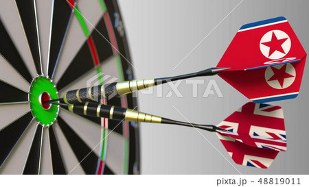 Flags of North Korea and the United Kingdom on darts hitting bullseye of the target. International Flags of North Korea and the United Kingdom on darts hitting bullseye of the target. International 48819011