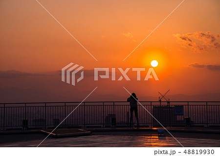 東京都市風景　ビル屋上から落日を見る女性 48819930