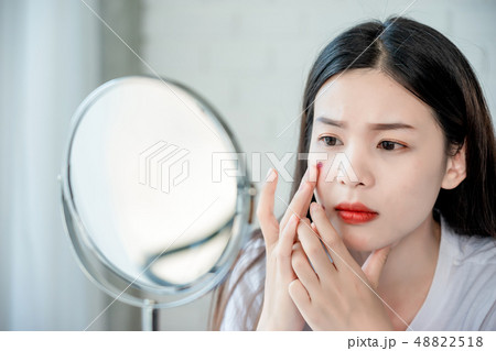 Asian teenage woman looking at mirror and squeeze Asian teenage woman looking at mirror and squeeze 48822518