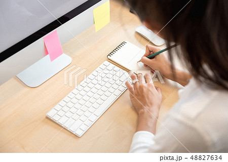 Woman writing note on paper at the table in the 48827634