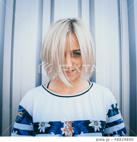 Portrait of cute girl with white short hairstyle. Her hair cover half face. She is looking forward Portrait of cute girl with white short hairstyle. Her hair cover half face. She is looking forward 48829890