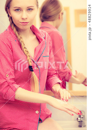 Woman applying hand cream on hands Woman applying hand cream on hands 48829914