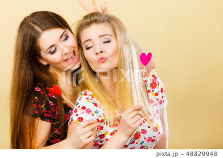 Two happy women holding heart on stick 48829948