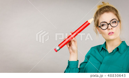 Woman confused thinking, big pencil in hand 48830643