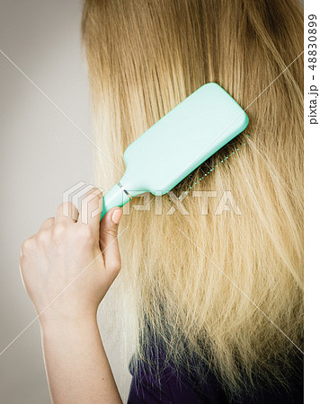 Blonde woman brushing hair back view 48830899