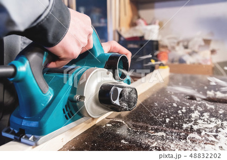 The hands of a carpenter working woodworking power tools. Close up of the work of the electric 48832202