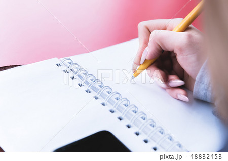 Close-up from behind the back of a young woman in a winter polto is holding a ballpoint pen and is 48832453