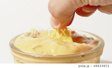 Dipping tortilla chip into cheese sauce, extreme close-up shot Dipping tortilla chip into cheese sauce, extreme close-up shot 48834953