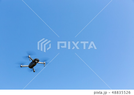 A drone flying against the blue sky A drone flying against the blue sky 48835526