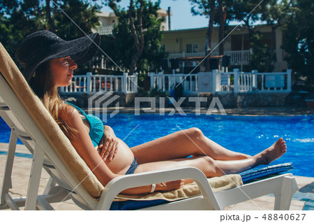 pregnant woman sunbathing on a lounger by the pool pregnant woman sunbathing on a lounger by the pool 48840627