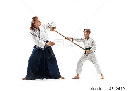 Man and teen boy fighting with wooden swords at Aikido training in martial arts school Man and teen boy fighting with wooden swords at Aikido training in martial arts school 48840639