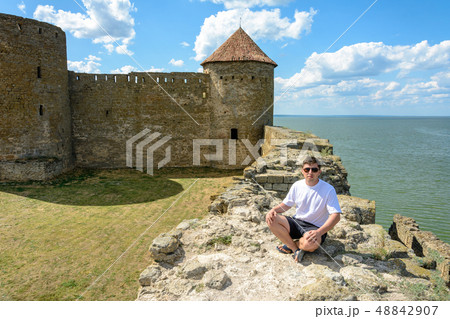 Young man in sunglasses sits on the wall of the 48842907