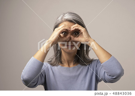 Asian mature woman does ok gesture like binoculars. 48843036