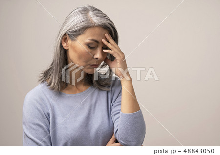 Mature Asian woman touches her forehead in distress 48843050