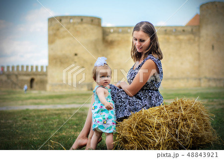 A young mother with her daughter sits on a straw 48843921